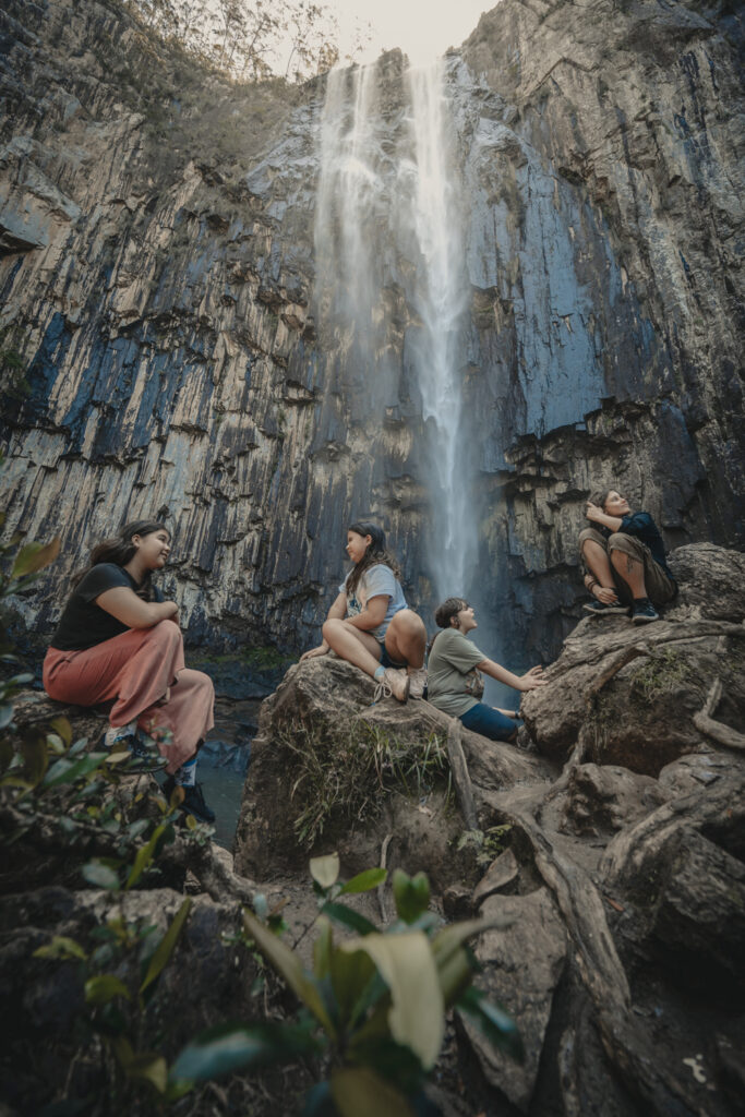 Group on a tour sitting at the base of Minyon Falls